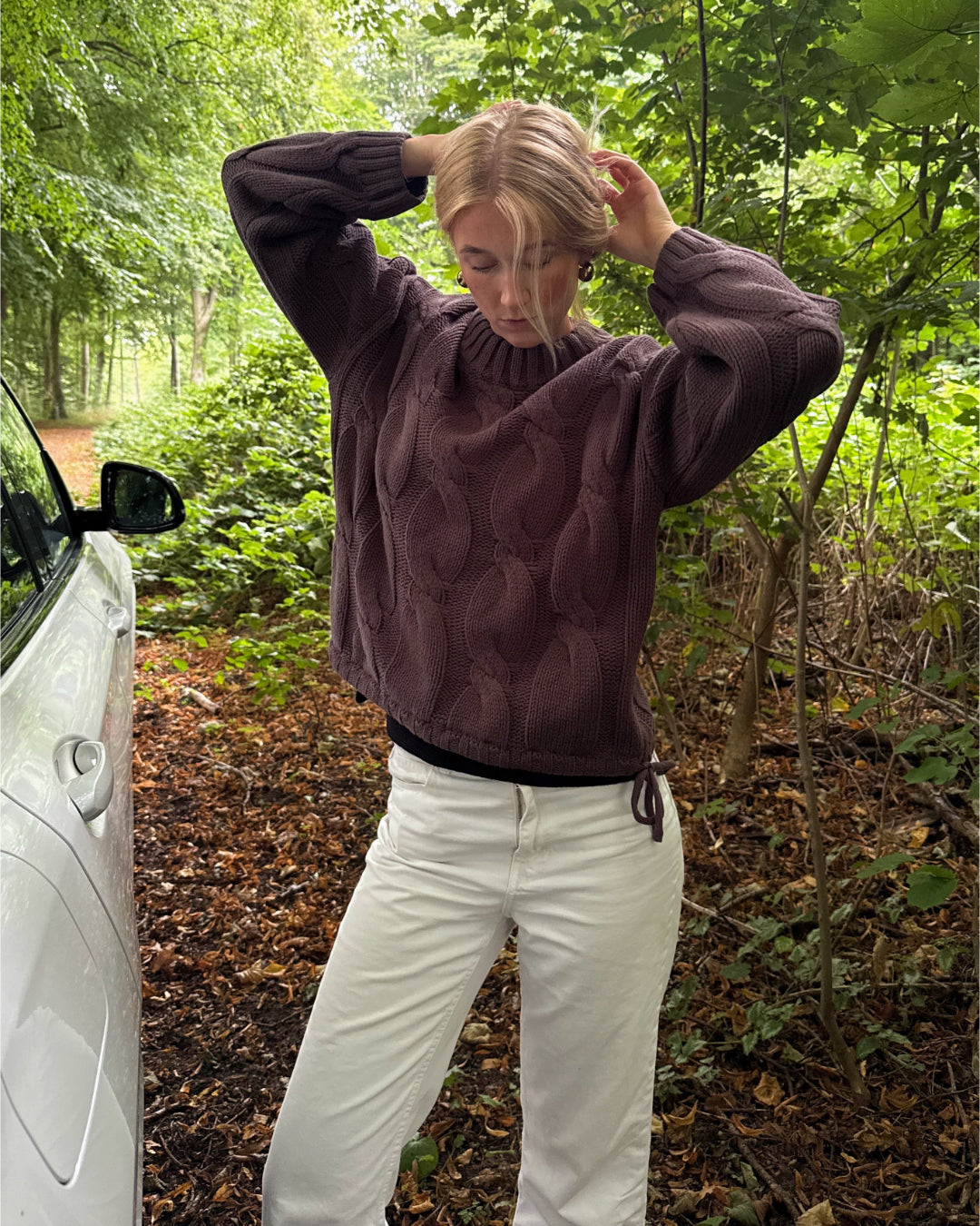 Modelfoto af pige i en brun Bay striktrøje og hvide Nanna jeans. Alt er fra BySofieSønderby