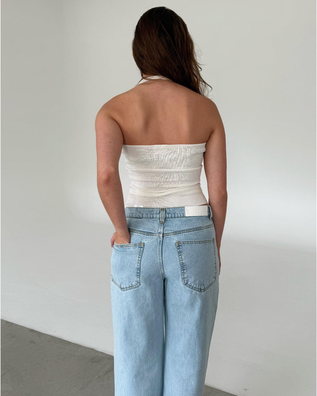 Modelfoto af pige med CHRISTINE top, hvid og NANNA jeans, lyseblå - begge fra fra BySofieSønderby