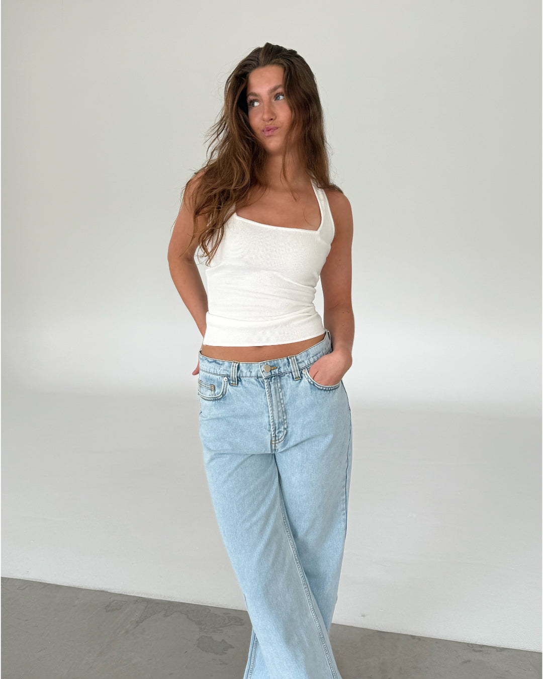Modelfoto af pige med CHRISTINE top, hvid og NANNA jeans, lyseblå - begge fra fra BySofieSønderby