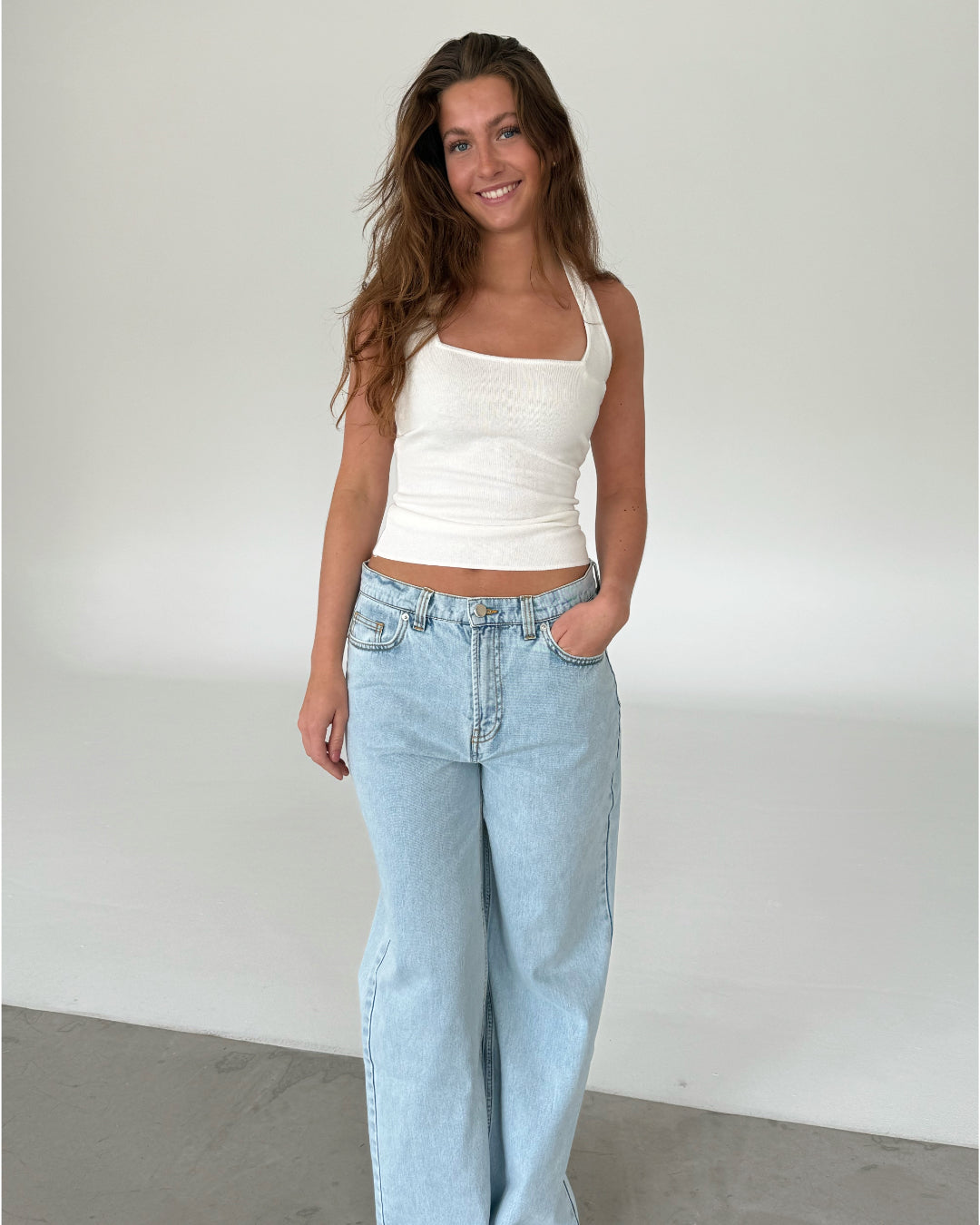 Modelfoto af pige med CHRISTINE top, hvid og NANNA jeans, lyseblå - begge fra fra BySofieSønderby