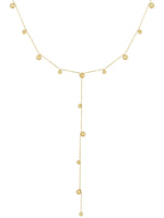 Kæde af guld med små kugler jævnt fordelt; en lang vedhængende sektion hænger centralt. Baggrunden er enkel og hvid, hvilket fremhæver smykkets elegante design.