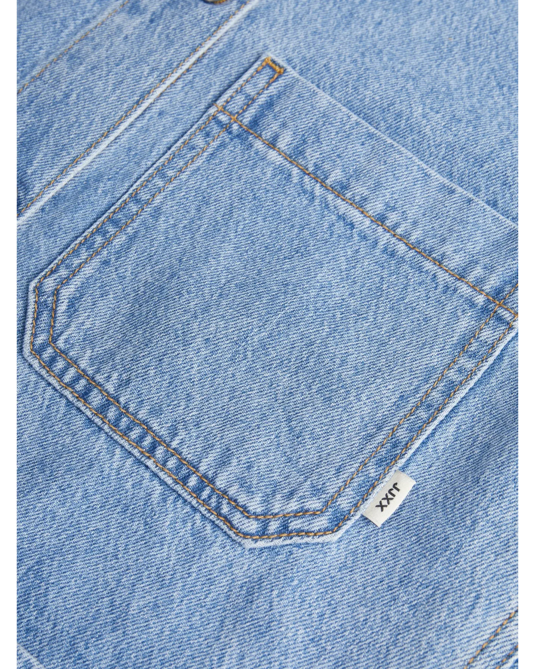 En jeanslomme med gul syning, der sidder fast på lyseblåt denimstof. Et lille hvidt mærke med teksten "JILX" stikker ud fra siden af lommen.