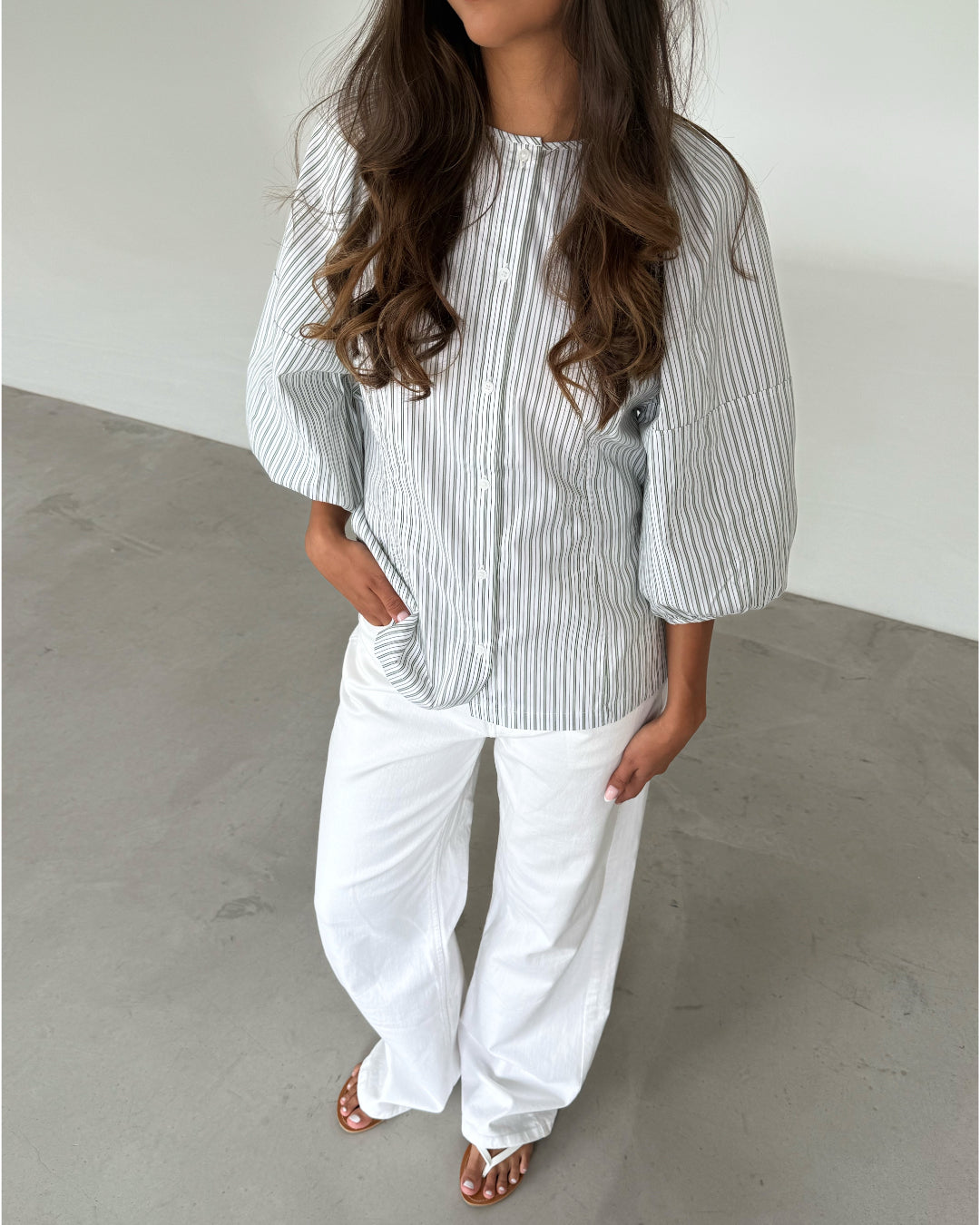 Modelfoto af pige som bærer grøn-hvid stribet HELEN skjorte og hvide jeans. Alt er fra BySofieSønderby