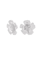 To klare blomsterformede øreringe med detaljerede kronblade ligger ved siden af hinanden på en hvid baggrund.