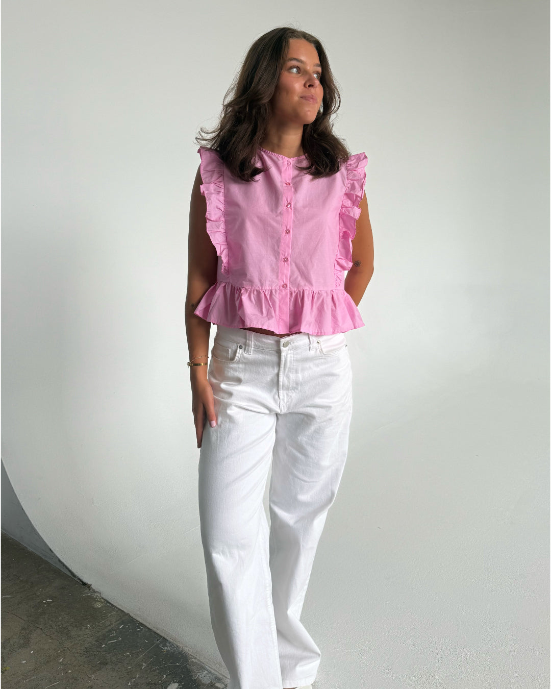 Modelfoto af pige som bærer Hope Cilie top i lyserød, samt et par hvide Nanna jeans. Alt fra By Sofie Sønderby