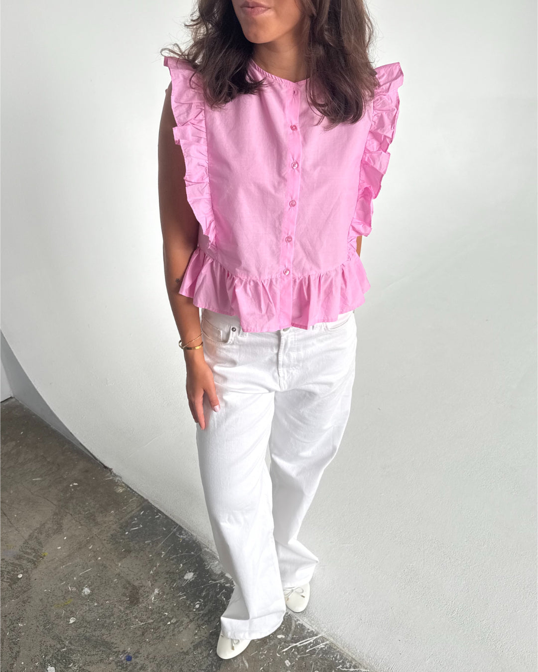 Modelfoto af pige som bærer Hope Cilie top i lyserød, samt et par hvide Nanna jeans. Alt fra By Sofie Sønderby
