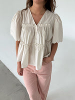Modelfoto af pige som bærer creme-farvet HOPE top med v-hals og lyserøde jeans. Alt er fra BySofieSønderby