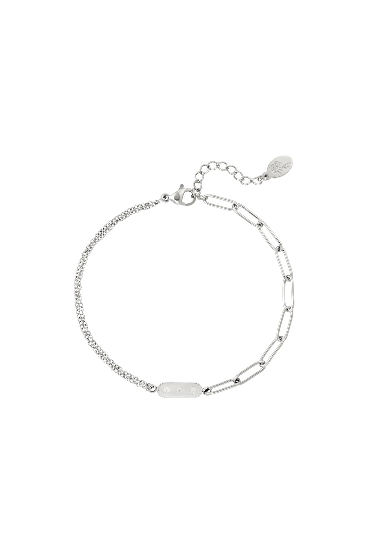 Armbånd i sølv med to forskellige kædeled, sammenføjes med en lille plade med stjernedetaljer. Forlængerkæde med rund vedhæng. Enkel og moderne stil mod hvid baggrund.