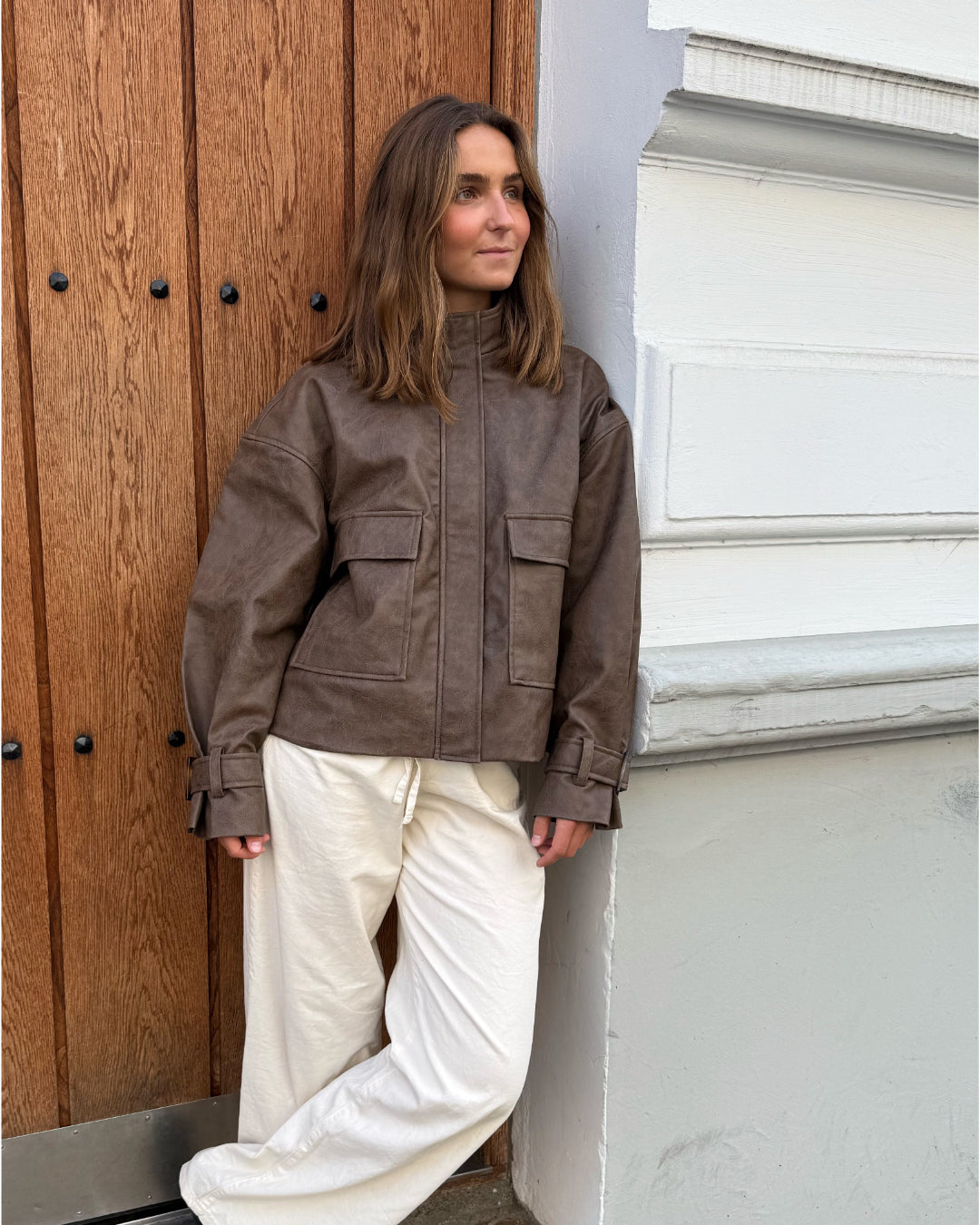 Modelfoto af pige i brun Lama læder jakke og beigefarvede Arianna jeans. Alt er fra BySofieSønderby