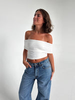 Modelfoto af pige som bærer en Leia top i hvid, samt et par hvide Nanna jeans. Alt fra By Sofie Sønderby