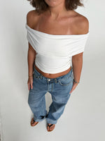 Modelfoto af pige som bærer en Leia top i hvid, samt et par hvide Nanna jeans. Alt fra By Sofie Sønderby