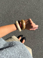 Modelfoto af Leona armbånd sæt bestående af 3 armbånd i brunlige nuancer. Baggrund er grå. Fra BySofieSønderby