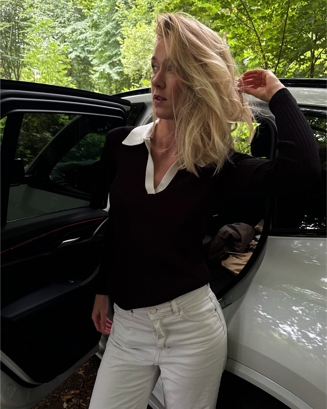 Modelfoto af pige i en sort Lidya polo og hvide Nanna jeans. Alt er fra BySofieSønderby