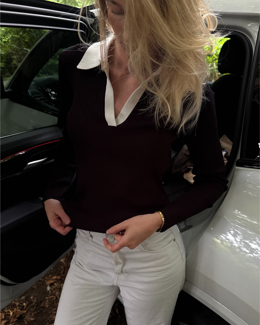 Modelfoto af pige i en sort Lidya polo og hvide Nanna jeans. Alt er fra BySofieSønderby