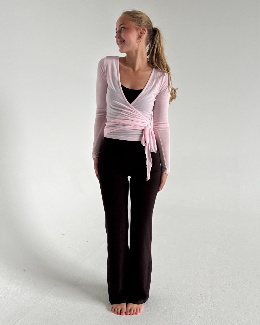 Modelfoto af pige i lyserød Luna wrap bluse og brune Sania bukser. Fra BySofieSønderby
