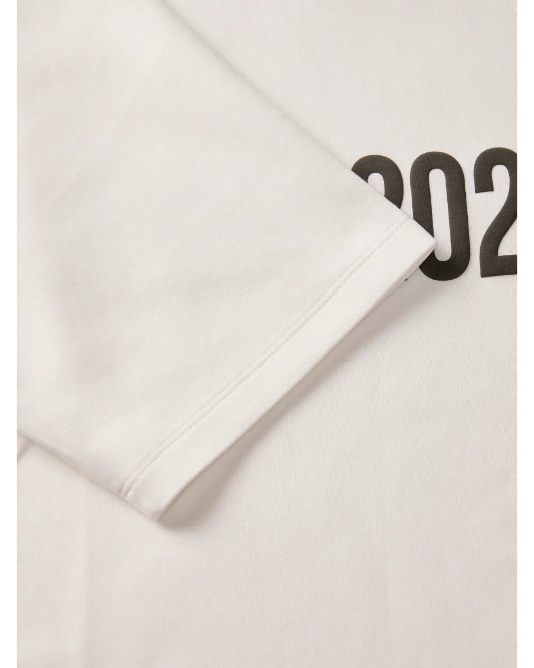 En hvid T-shirt ligger fladt med ærmet foldet. Tallet "202" er trykt i sort på stoffet.