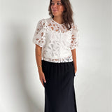 Modelfoto af pige som bærer en Rose bluse i hvid, samt en Breeze nederdel i navy. Alt fra By Sofie Sønderby