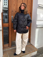 Modelfoto af pige i sort Stella jakke og beigefarvede Arianna jeans. Alt er fra BySofieSønderby