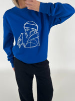 Blå sweatshirt med line art af en person med en flaske. Personen holder en hånd nær ansigtet. Baggrunden er neutral.