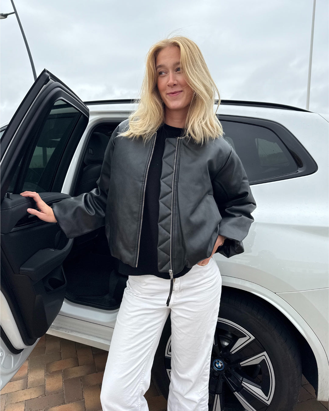 Modelfoto af pige der bærer Trudea jakke i sort udenpå en sort t-shirt, derudover har hun hvide Nanna jeans på. Alt fra BySofieSønderby