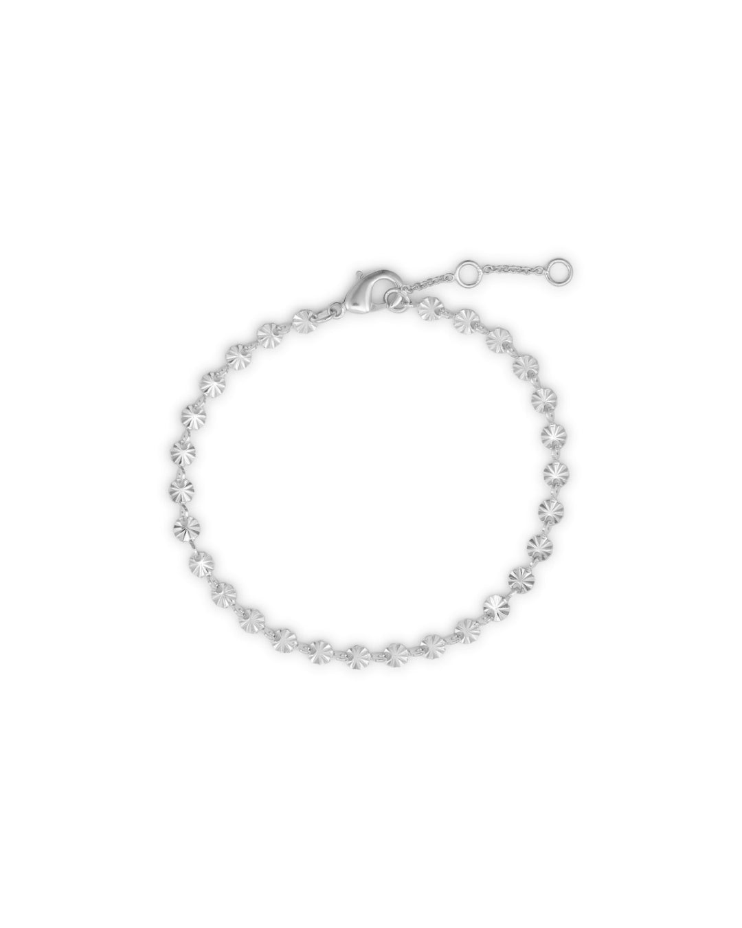 Et sølvfarvet armbånd ligger i en cirkel på en hvid baggrund. Armbåndet har små, cirkulære charms med stråleformede udskæringer.