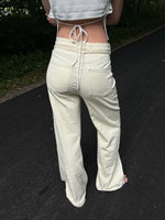 Modelfoto af pige i cremefarvede Adrianna jeans og hvid top. Alt er fra BySofieSønderby
