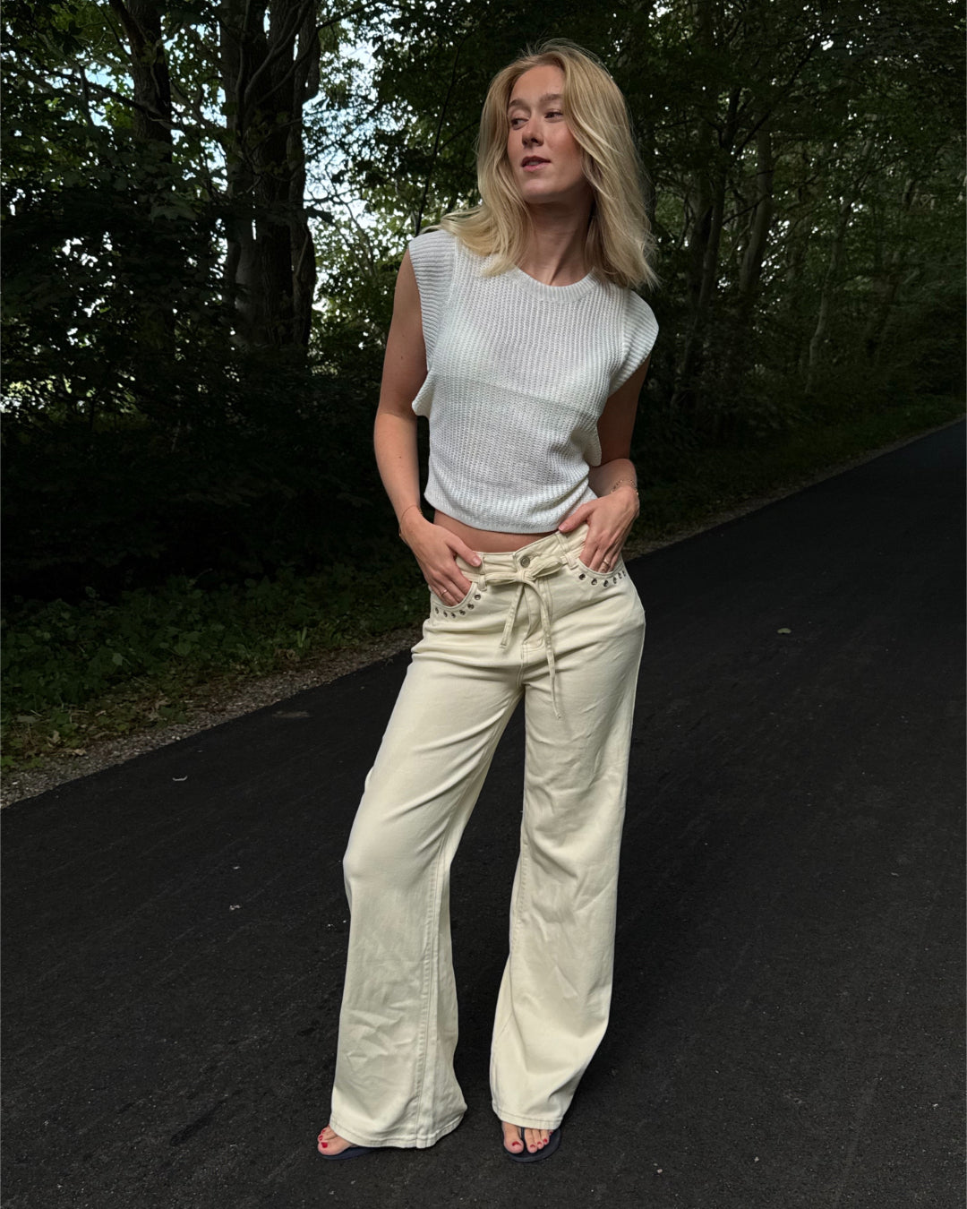 Modelfoto af pige i cremefarvede Adrianna jeans og hvid Taytum top. Alt er fra BySofieSønderby