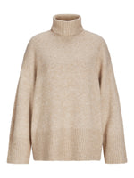 Beige striktrøje har en høj turtleneck og lange ærmer. Den har ribstrik i krave, manchetter og nederste kant, og hænger løst uden synlige dekorationer i en simpel, neutral baggrund.