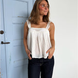 Modelfoto af pige som bærer en Amona top i hvid, samt et par mørkeblå jeans. Alt fra By Sofie Sønderby