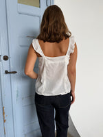 Modelfoto af pige som bærer en Amona top i hvid, samt et par mørkeblå jeans. Alt fra By Sofie Sønderby