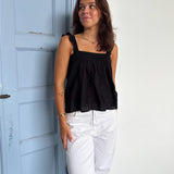 Modelfoto af pige som bærer en Amona top i sort, samt et par mørkeblå jeans. Alt fra By Sofie Sønderby