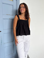 Modelfoto af pige som bærer en Amona top i sort, samt et par mørkeblå jeans. Alt fra By Sofie Sønderby