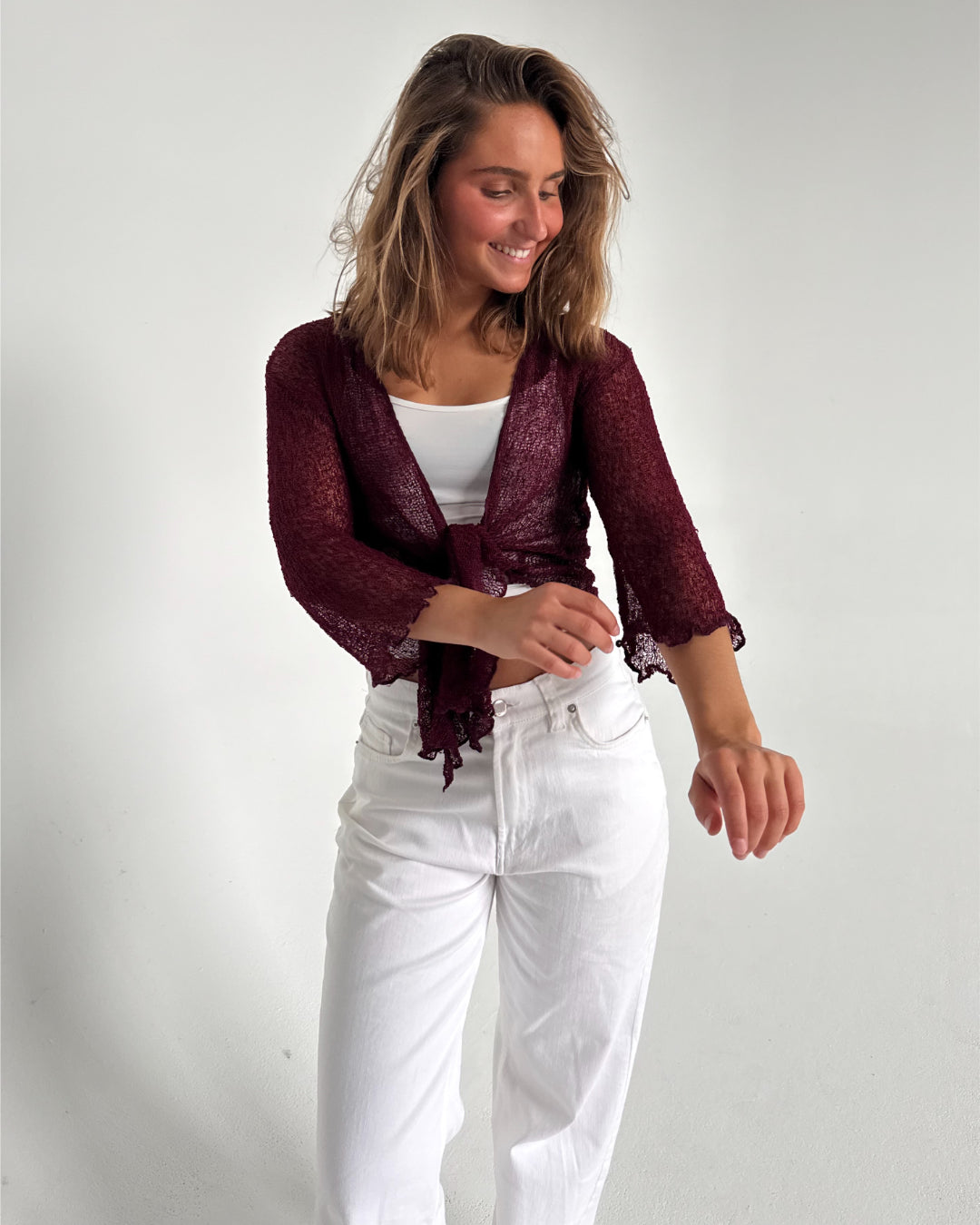 Modelfoto af pige som bærer en Arabella bluse i bordeaux, samt et par hvide jeans. Alt fra By Sofie Sønderby