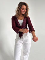 Modelfoto af pige som bærer en Arabella bluse i bordeaux, samt et par hvide jeans. Alt fra By Sofie Sønderby