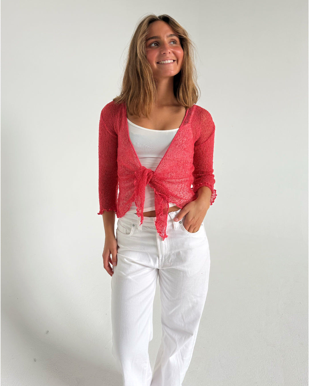Modelfoto af pige som bærer en Arabella bluse i coral, samt et par hvide jeans. Alt fra By Sofie Sønderby