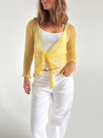 Modelfoto af pige som bærer en Arabella bluse i gul, samt et par hvide jeans. Alt fra By Sofie Sønderby
