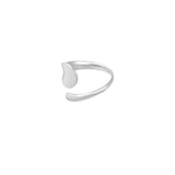 Sølvfarvet finger-ring med åbent design og dråbeformet detalje, ligger mod en hvid baggrund. Ringens minimalistiske stil fremhæves i det enkle, moderne design.