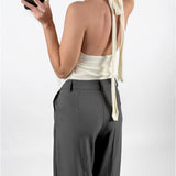 Modelfoto af pige med cremefarvet ASHLYN halterneck top, samt grå MILAN bukser. Set bagfra. Alt er fra BySofieSønderby