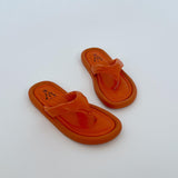 Orange sandaler ligger stille på en hvid baggrund. Sandalerne har en logoindgravering "M CINV 36".