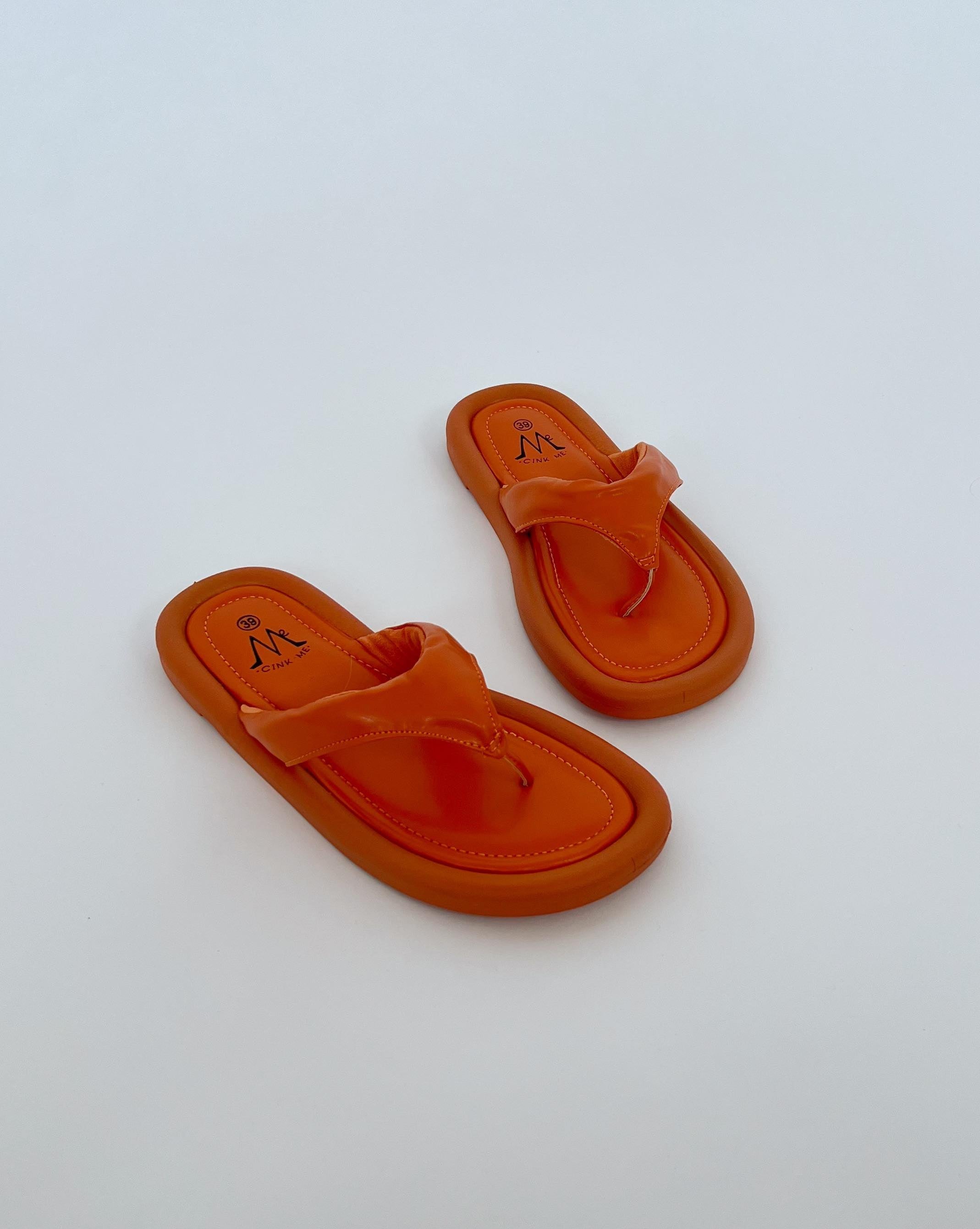 Orange sandaler ligger stille på en hvid baggrund. Sandalerne har en logoindgravering "M CINV 36".