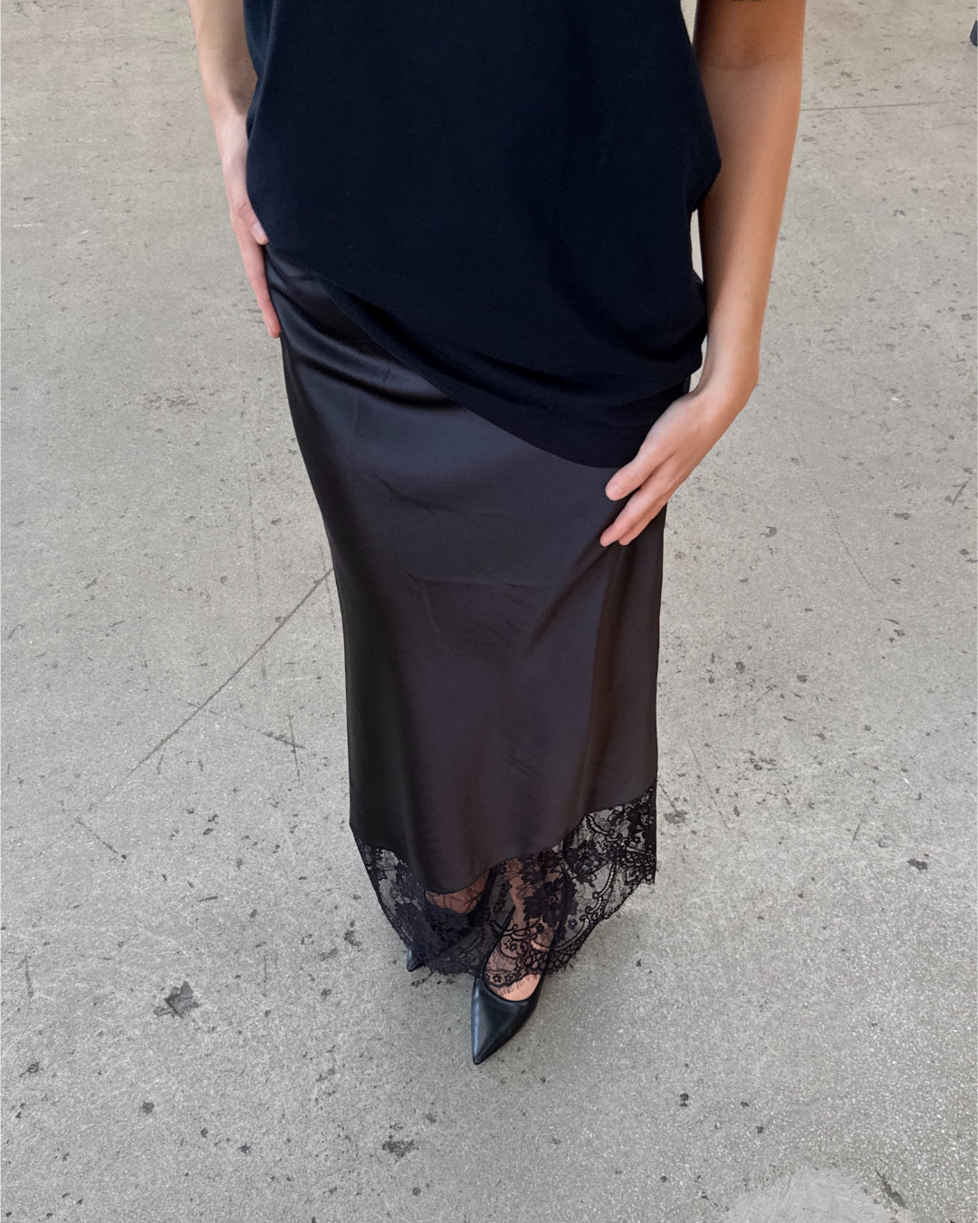 Modelfoto af pige i sort BILLIE nederdel, samt sort t-shirt. Alt er fra BySofieSønderby.