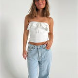 Modelfoto af pige der bærer en hvid stropløs Bonnie top, samt lyseblå Nanna jeans. Alt fra BySofieSønderby