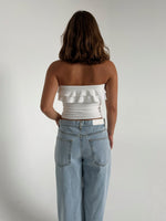 Modelfoto af pige der bærer en hvid stropløs Bonnie top, samt lyseblå Nanna jeans. Alt fra BySofieSønderby