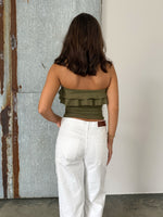 Modelfoto af pige der bærer en kaki farvet stropløs Bonnie top, samt hvide Nanna jeans. Alt fra BySofieSønderby