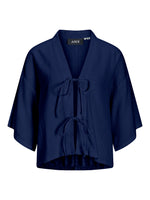 Mørkeblå kortærmet kimono med bindebånd foran. Påsyet mærke med teksten "JJXX" ved halsen. Baggrunden er hvid, hvilket fremhæver kimonoens farve og detalje.