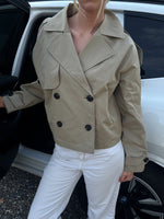 Modelfoto af pige der bærer Carlie jakke i beige, samt hvid bukser. Alt fra BySofieSønderby