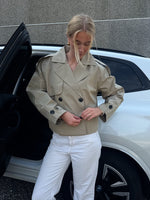 Modelfoto af pige der bærer Carlie jakke i beige, samt hvid bukser. Alt fra BySofieSønderby