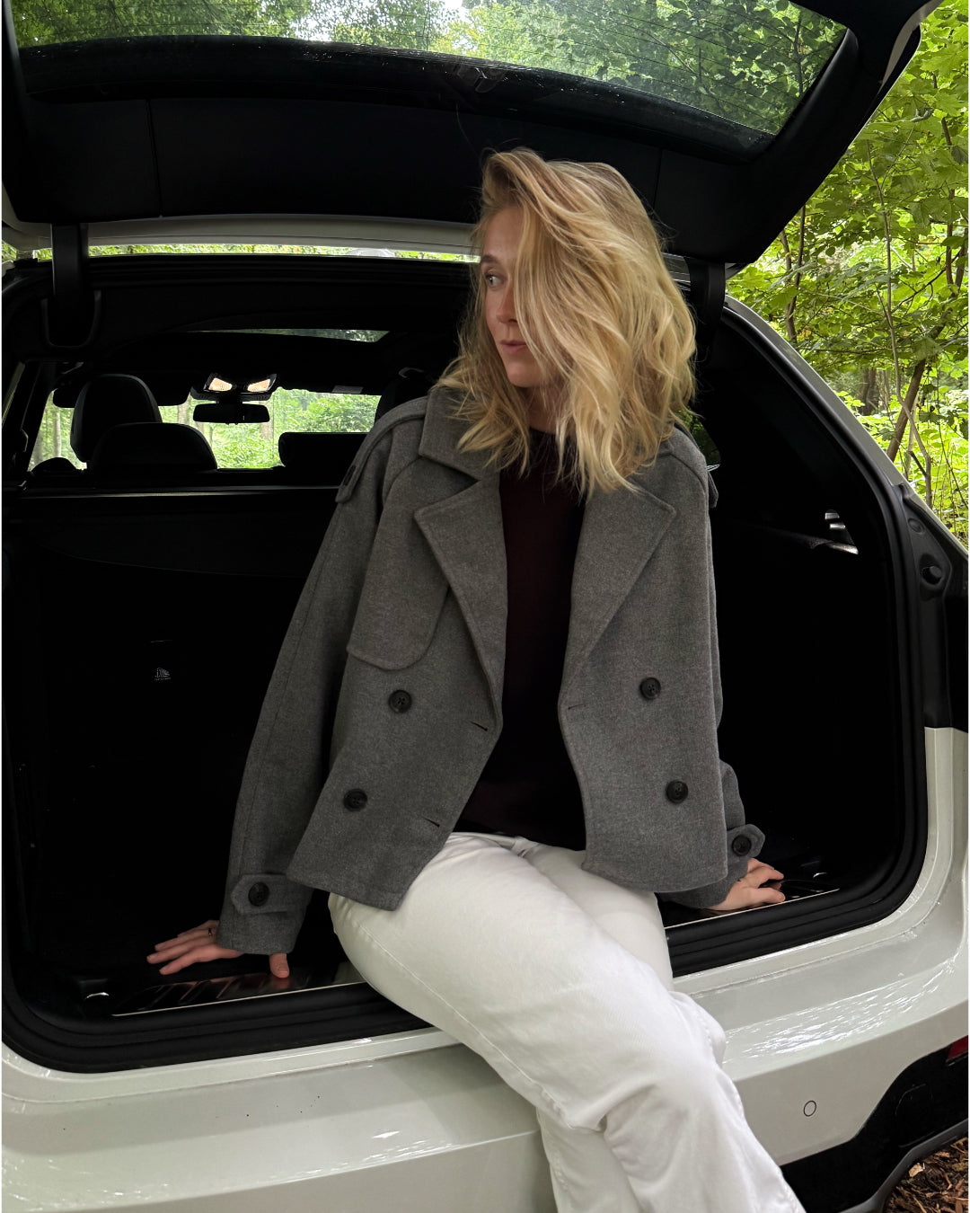 Modelfoto af pige i en grå Carlie jakke og hvide Nanna jeans. Alt er fra BySofieSønderby