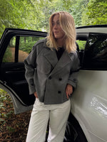 Modelfoto af pige i en grå Carlie jakke og hvide Nanna jeans. Alt er fra BySofieSønderby