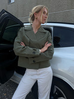 Modelfoto af pige der bærer Carlie jakke i kaki, samt hvid bukser. Alt fra BySofieSønderby